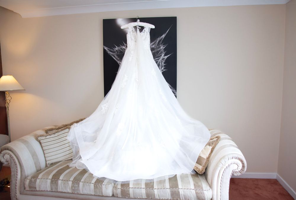 White wedding dress displayed on striped sofa against black and white wall art.