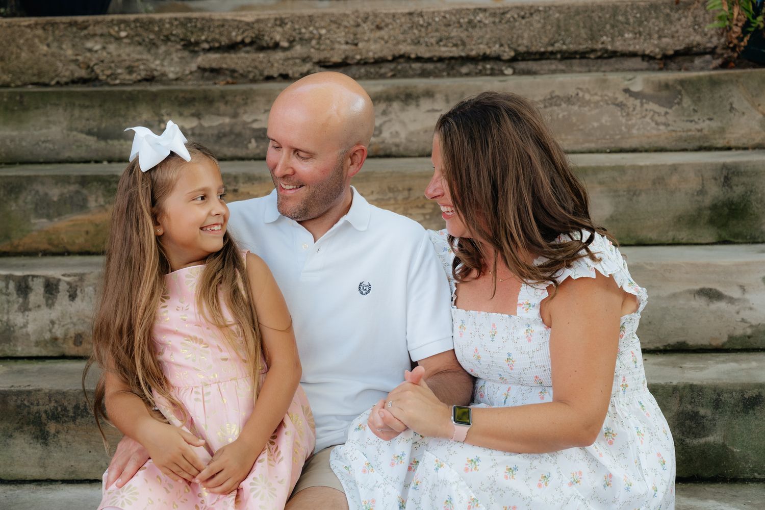 A happy family moment captured on stone steps outdoors on a sunny day.