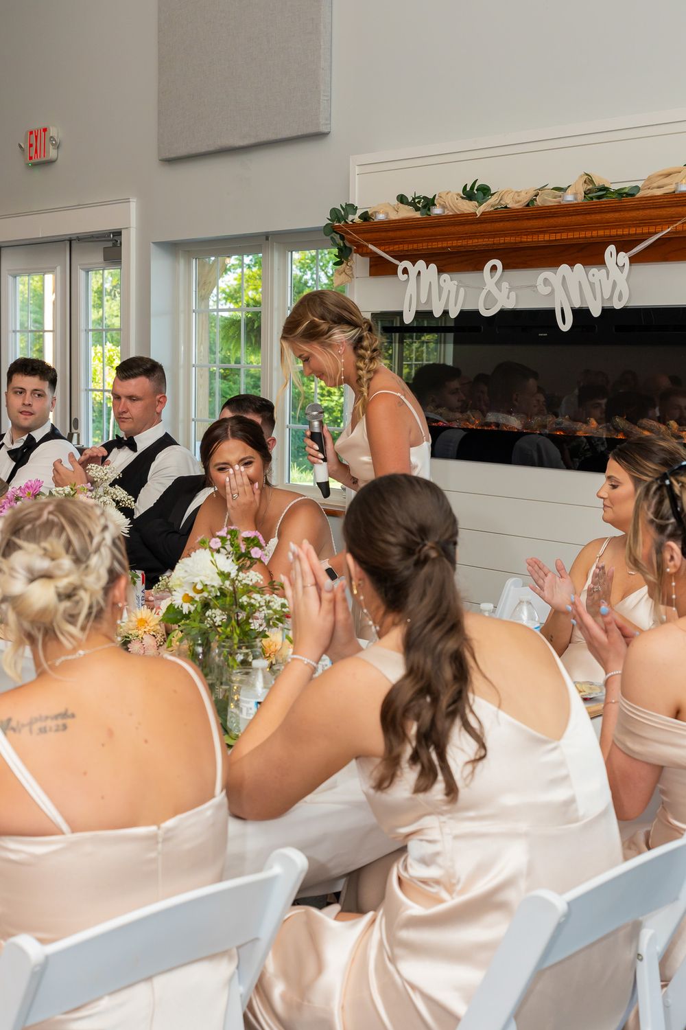 Wedding party seated in white chairs during an emotional ceremony moment.