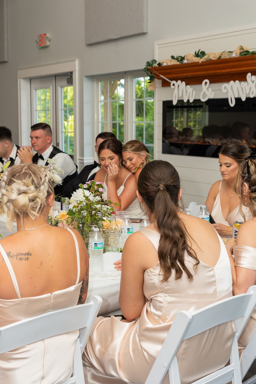 Bridesmaids in champagne satin dresses seated at reception tables.