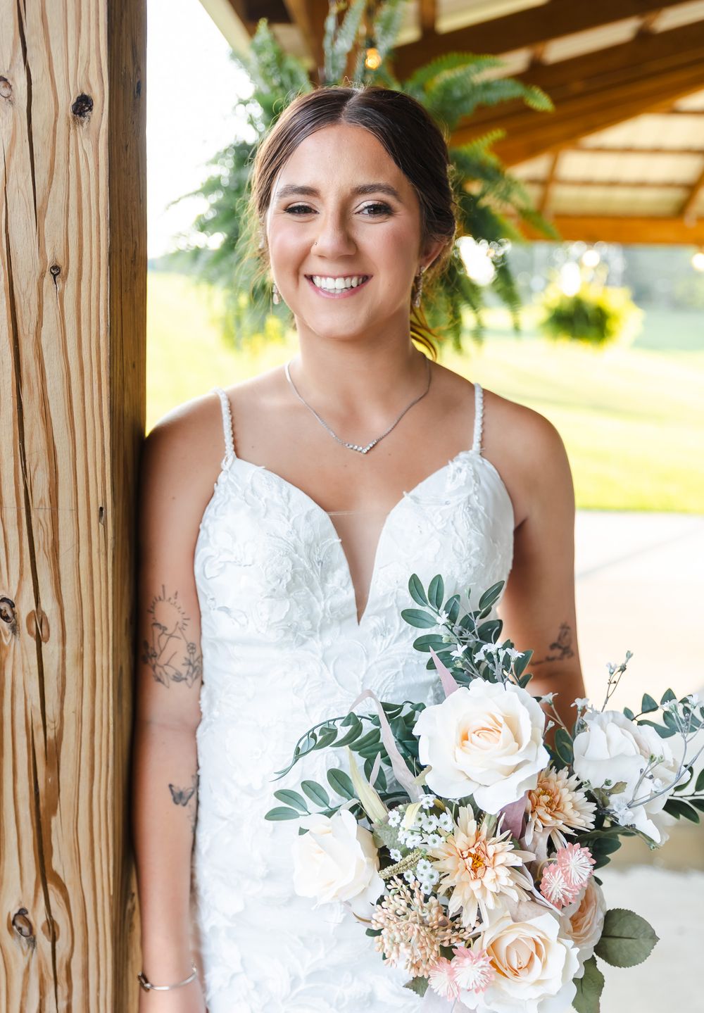 Bridal portrait under wooden gazebo with peach and white bouquet.