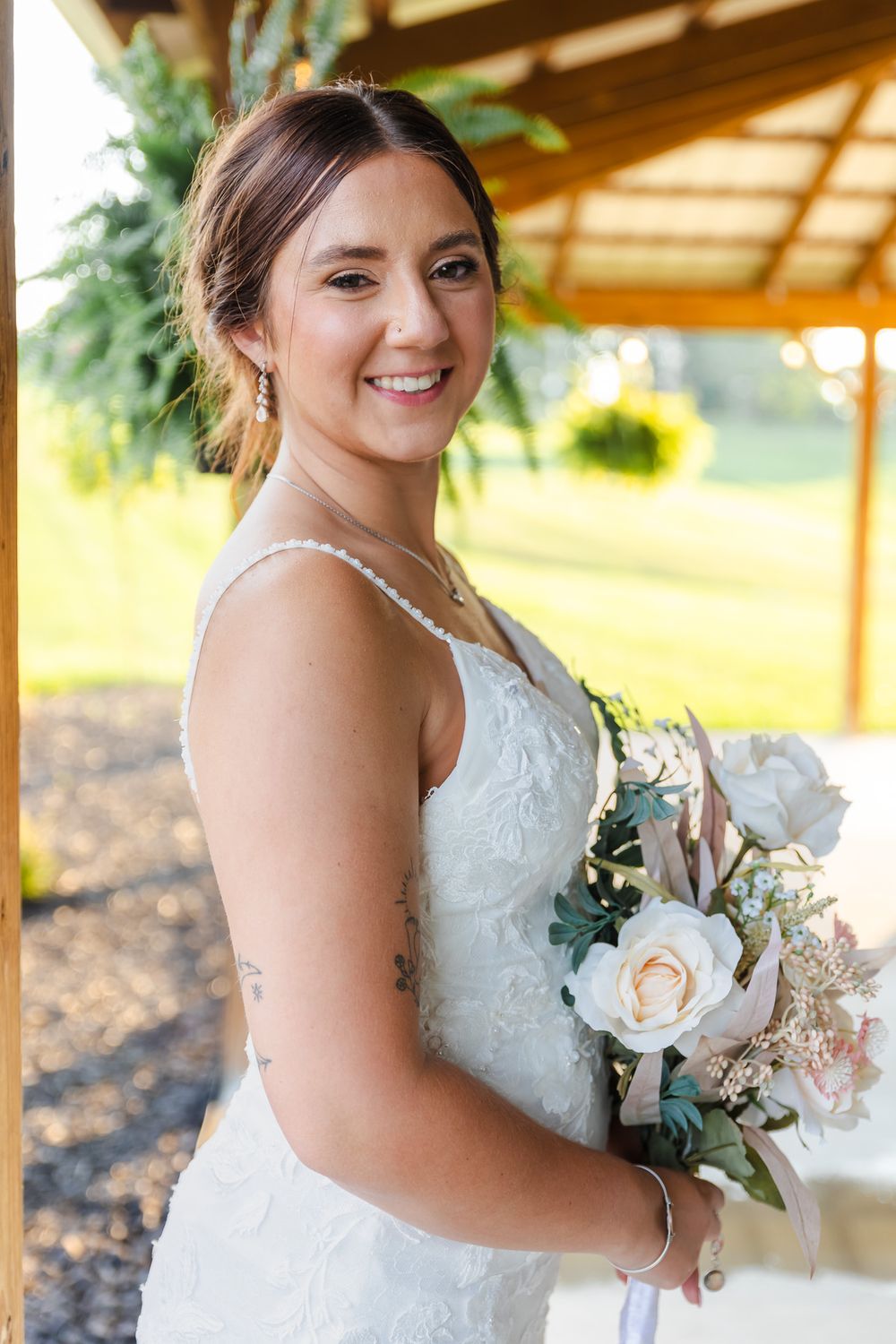 Bride holding elegant bouquet of peach roses and eucalyptus.
