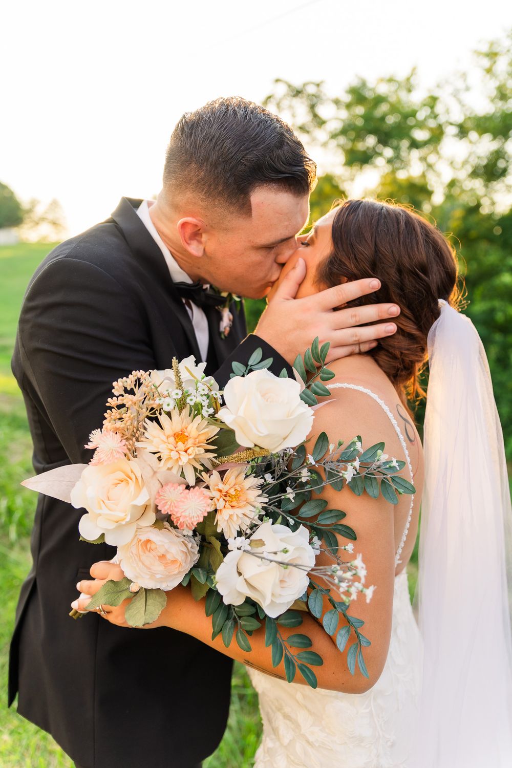 Romantic outdoor wedding photo with peach and white floral bouquet.