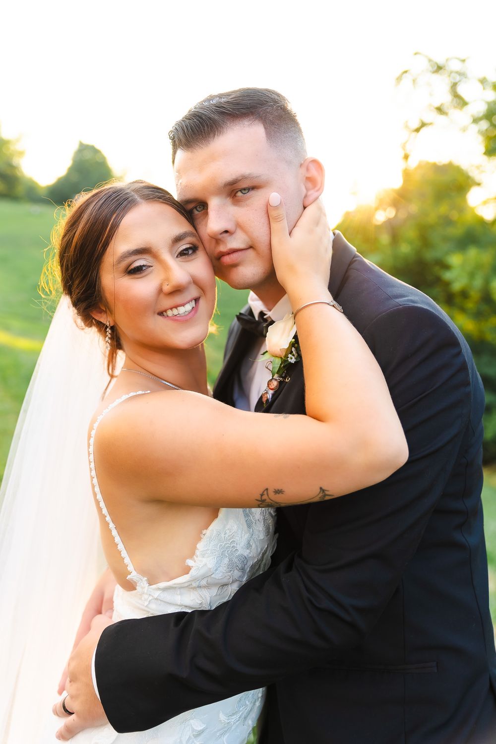 Newlyweds share tender moments during golden hour outdoor wedding photoshoot.