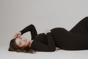 A series of artistic black and white maternity photos showing a pregnant woman in a black dress laying on the floor.