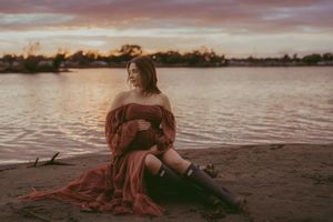 A serene sunset beach scene with silhouetted figures and flowing red fabric creating a romantic atmosphere.