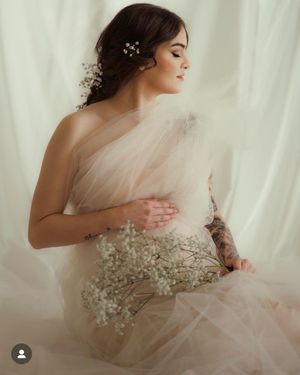 Ethereal bridal portrait with delicate tulle gown and baby's breath flowers in a dreamy light setting.