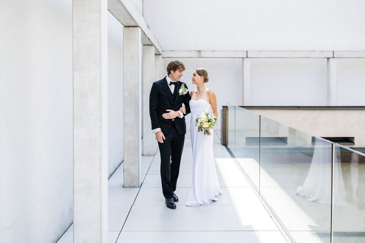 Elegant stately mansion with white facade serves as backdrop for wedding photo with blue car and flowing dress.