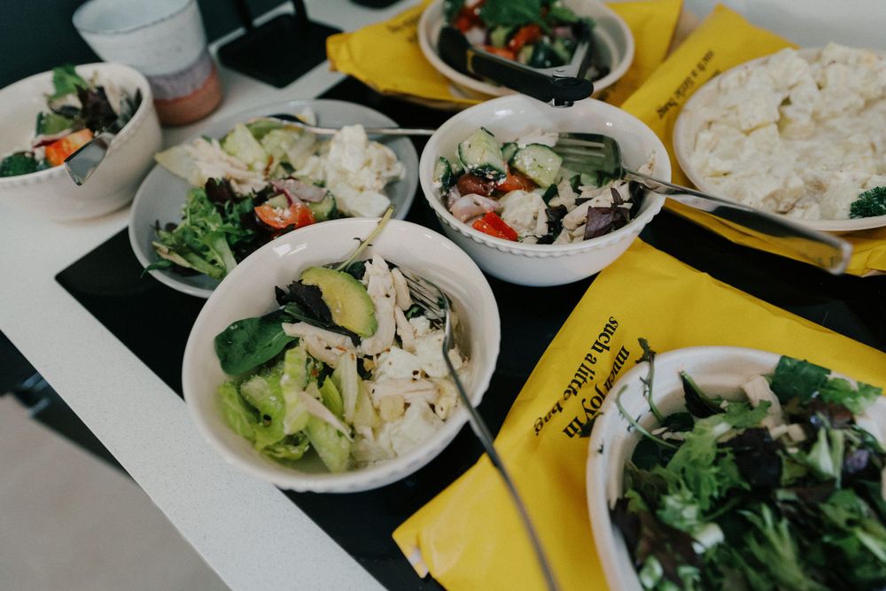 Fresh garden salads served in white bowls on yellow placemats at wedding reception.