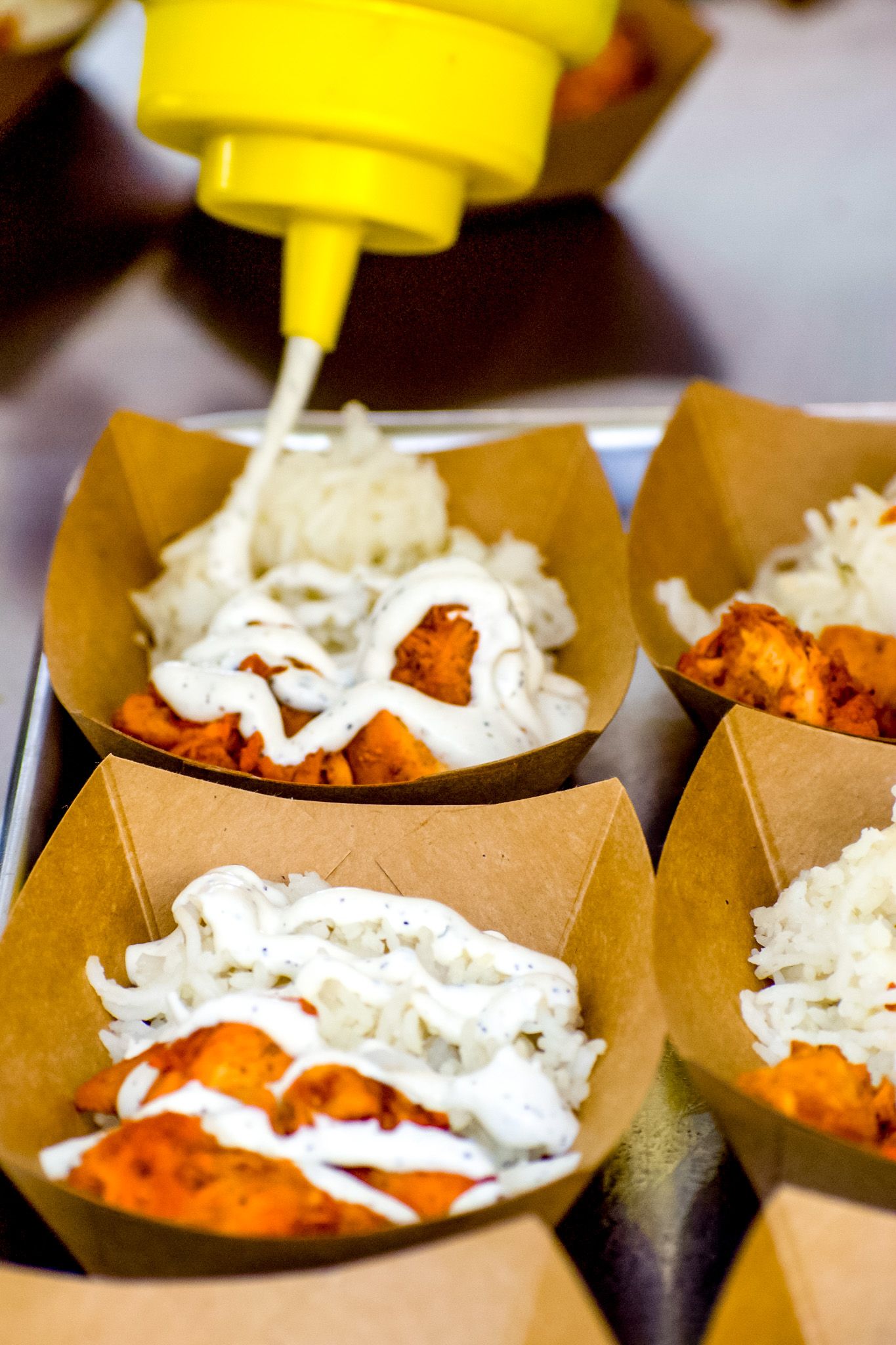 Paper boats filled with shredded cheese and spicy food served at a party or event.