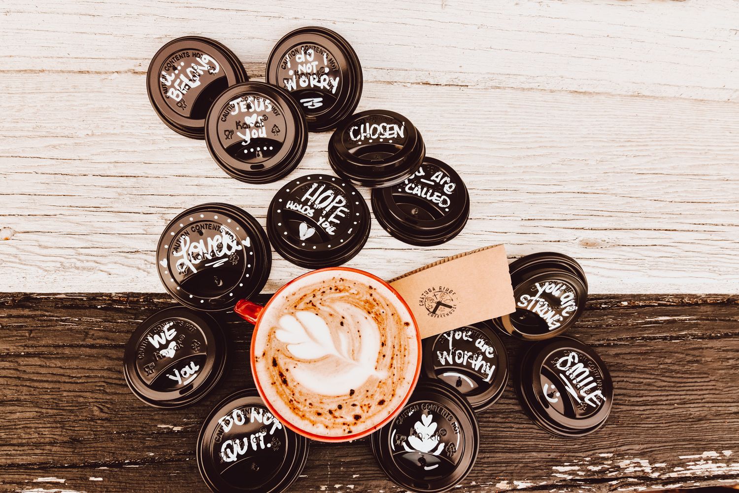 A collection of coffee cup lids arranged on a rustic wooden background.