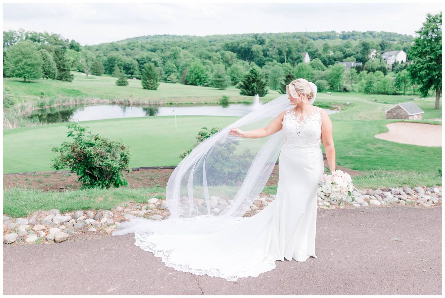 A wedding dress with a flowing veil captured on a scenic golf course with rolling green hills in the background.