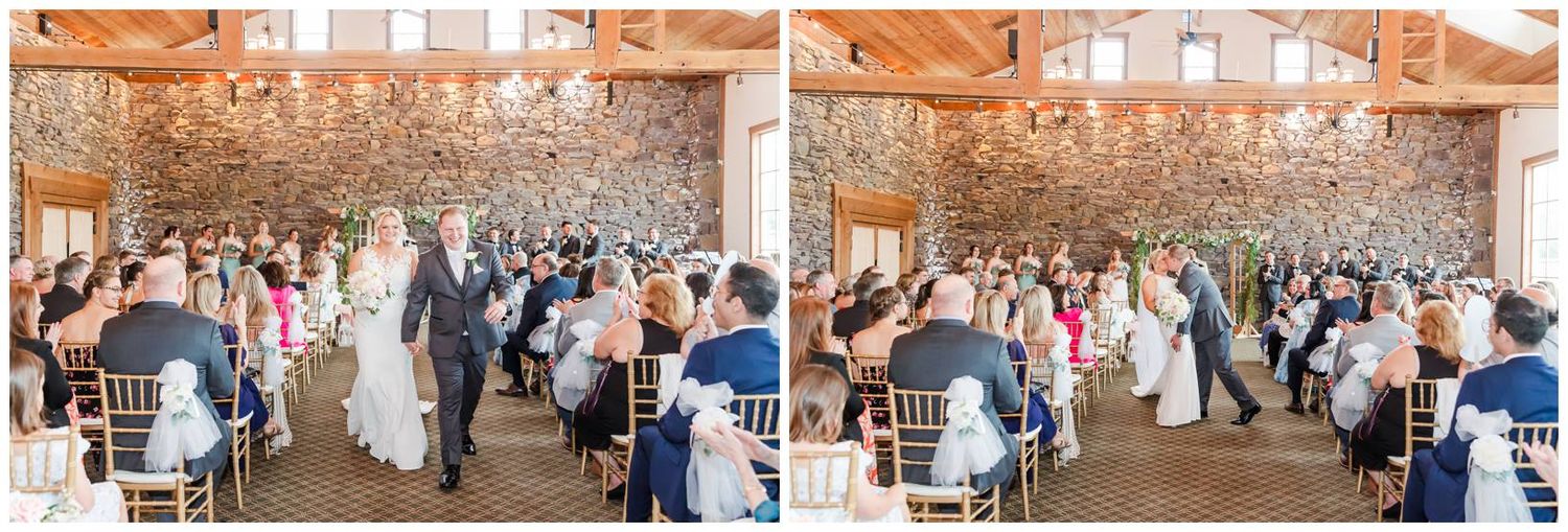 Wedding guests celebrate during a rustic barn reception with dancing and mingling under fairy lights and branches.