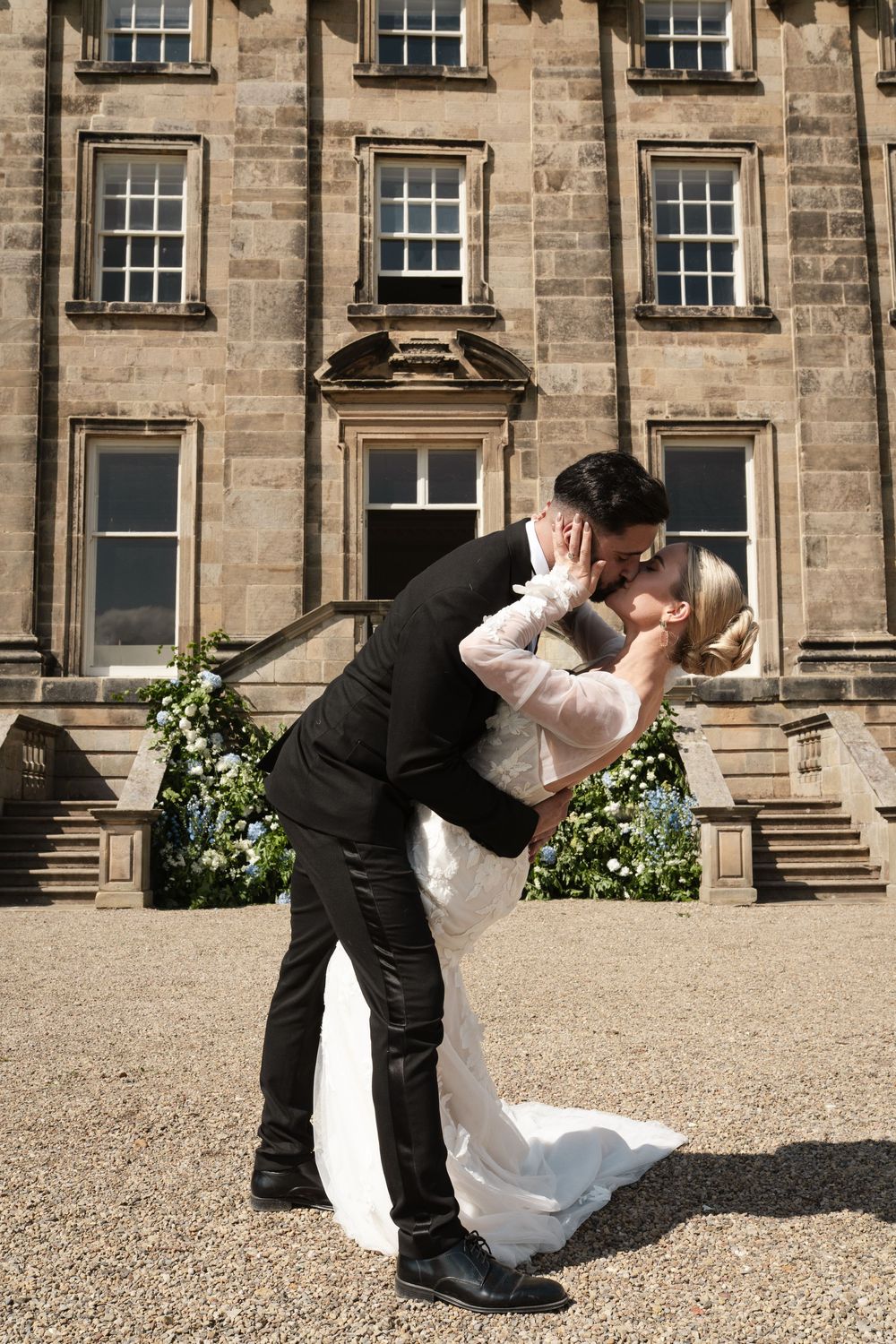 A romantic wedding dip pose in front of a grand stone building with elegant architecture.