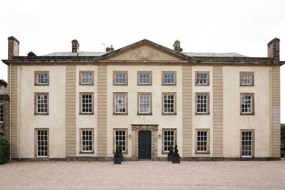 Symmetrical Georgian manor house with three stories and classic white facade.