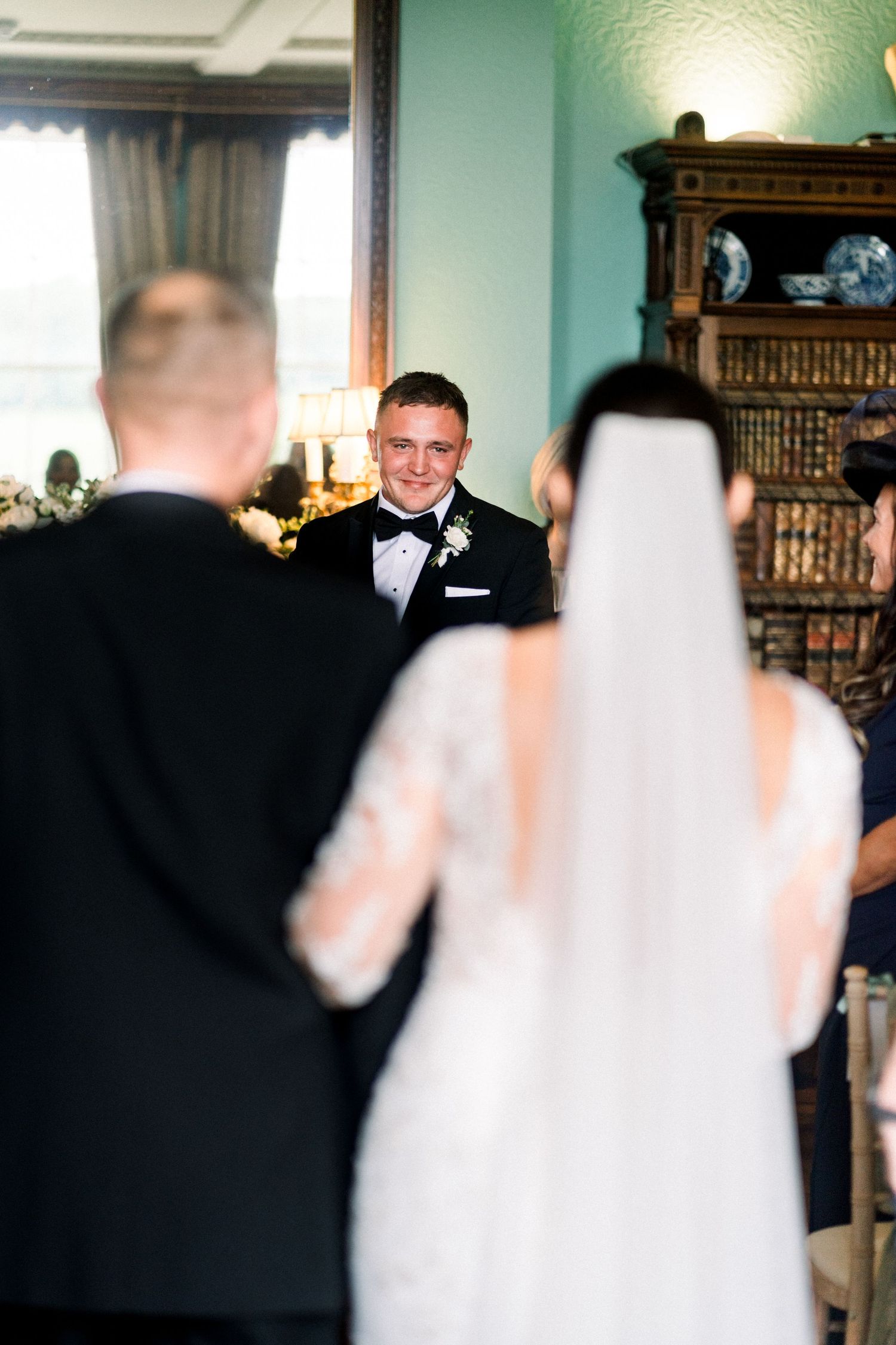 Bride & groom stand gazing up at grand cathedral-like architecture inside Nottingham Council House, with skylight, arches, and tall windows.