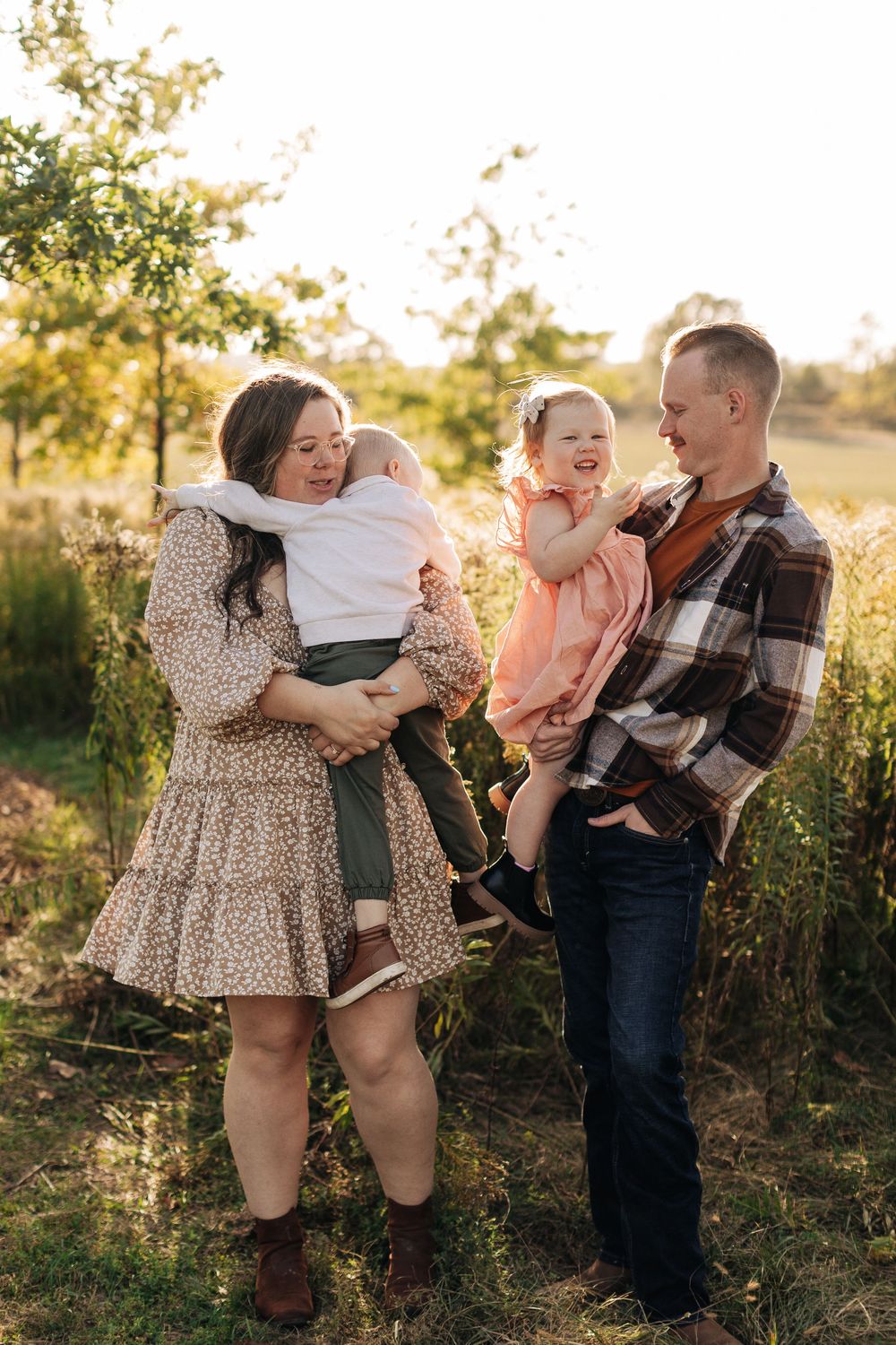 A loving family shares playful moments together in a sunlit field during golden hour.