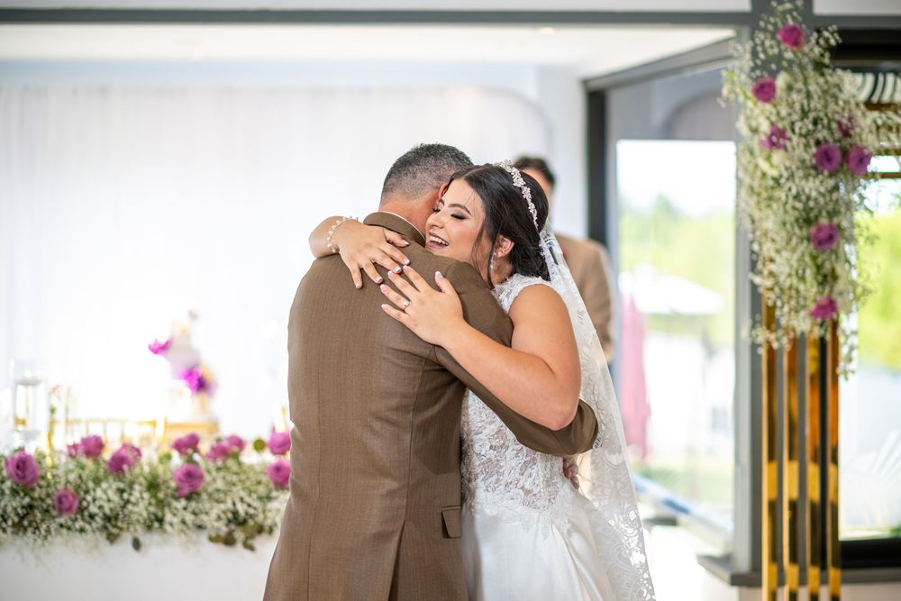An emotional embrace between two people at a wedding celebration surrounded by floral decorations.