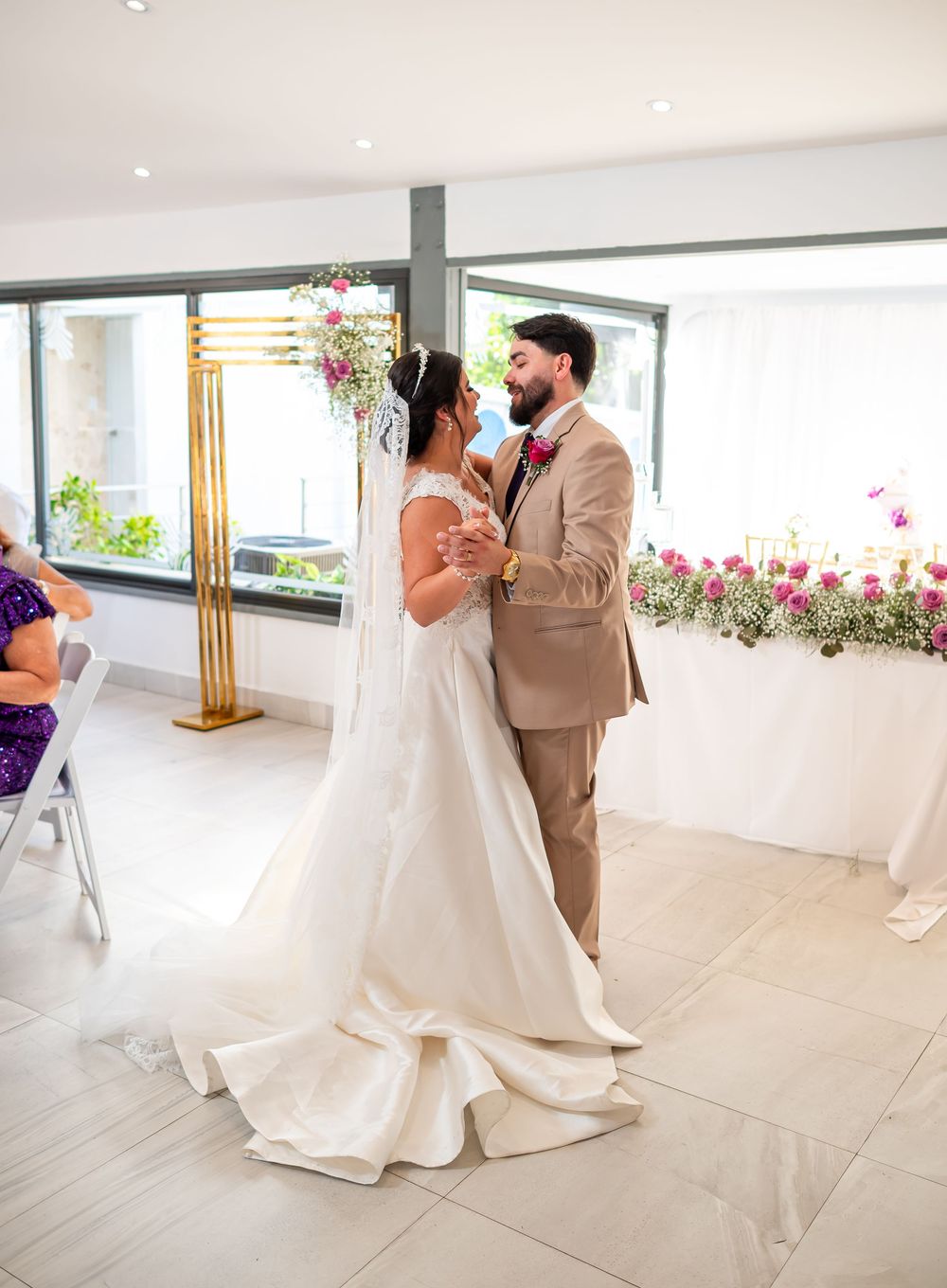 Bride in white gown and groom in tan suit sharing intimate moment during wedding ceremony.