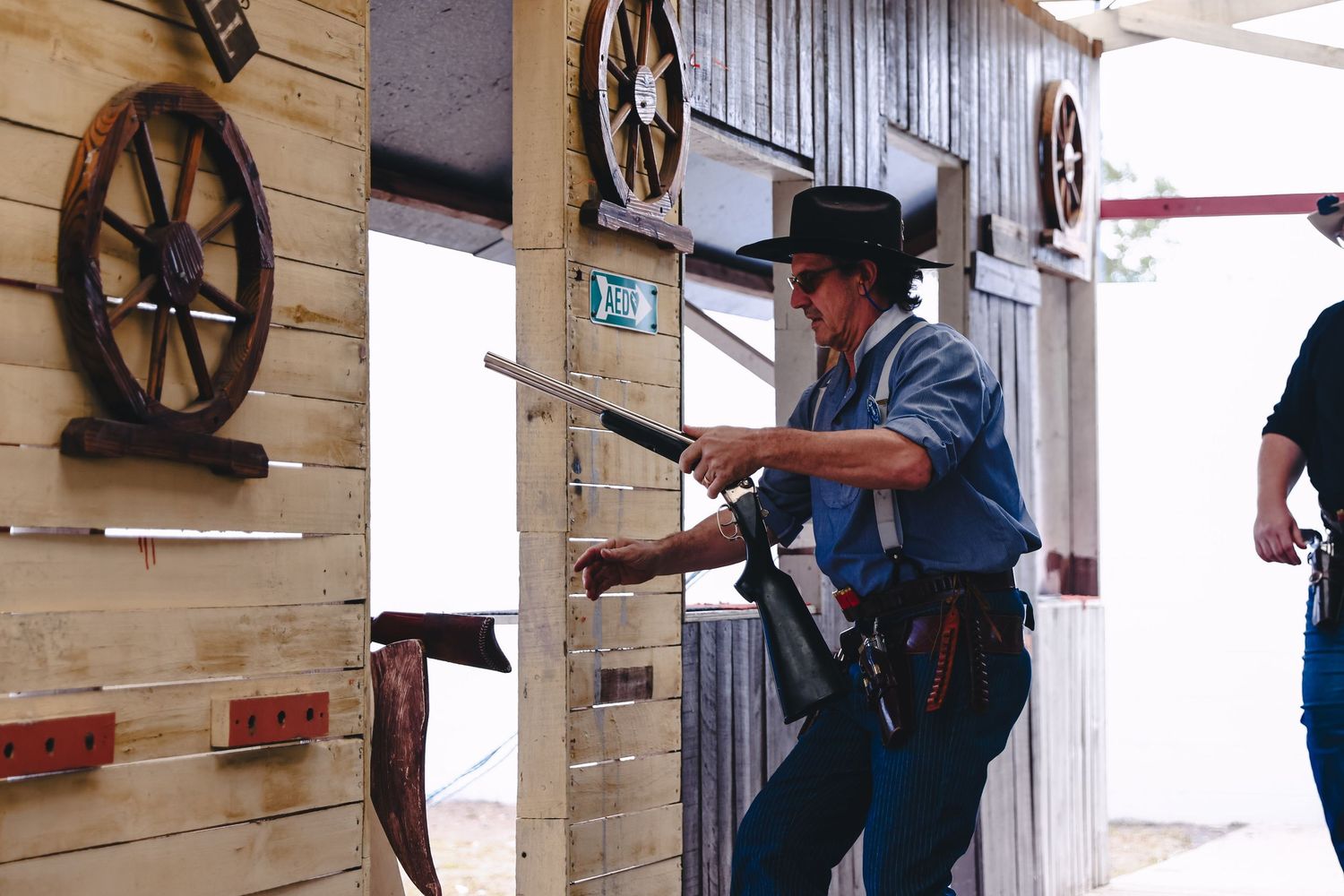 Person in uniform demonstrating safe firearm handling techniques at an indoor training facility.