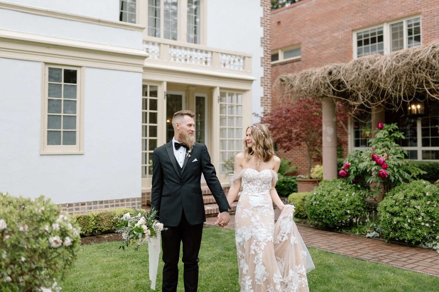 A couple walks through beautiful gardens together during an elegant wedding photo session at a country estate.