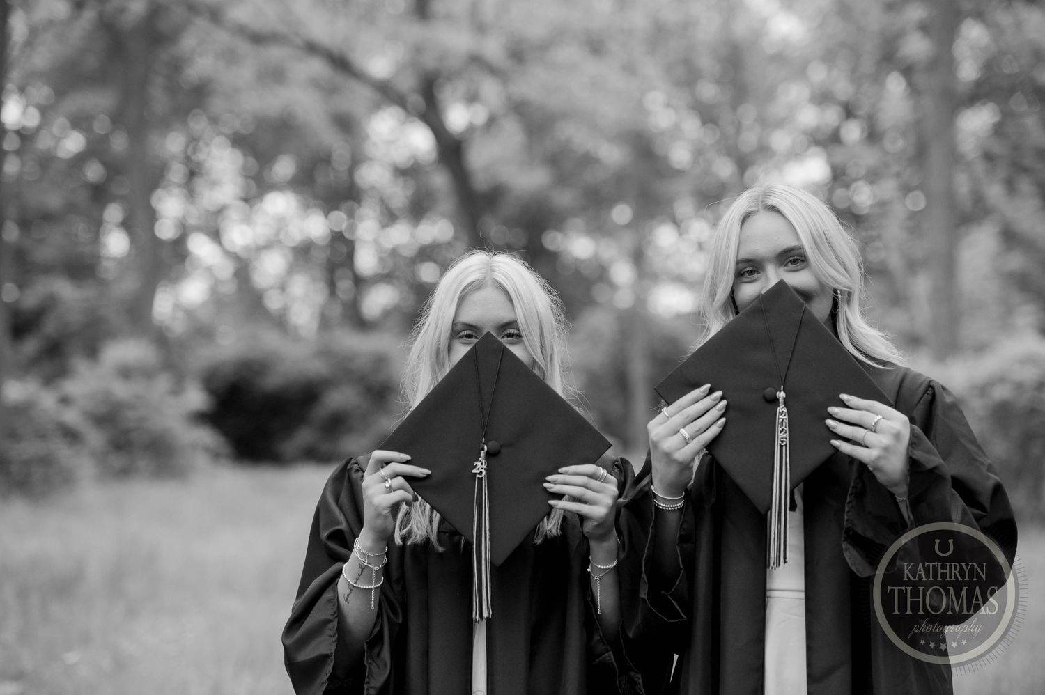 Two figures in black coats hold books in front of their faces while standing outdoors in a black and white photo.