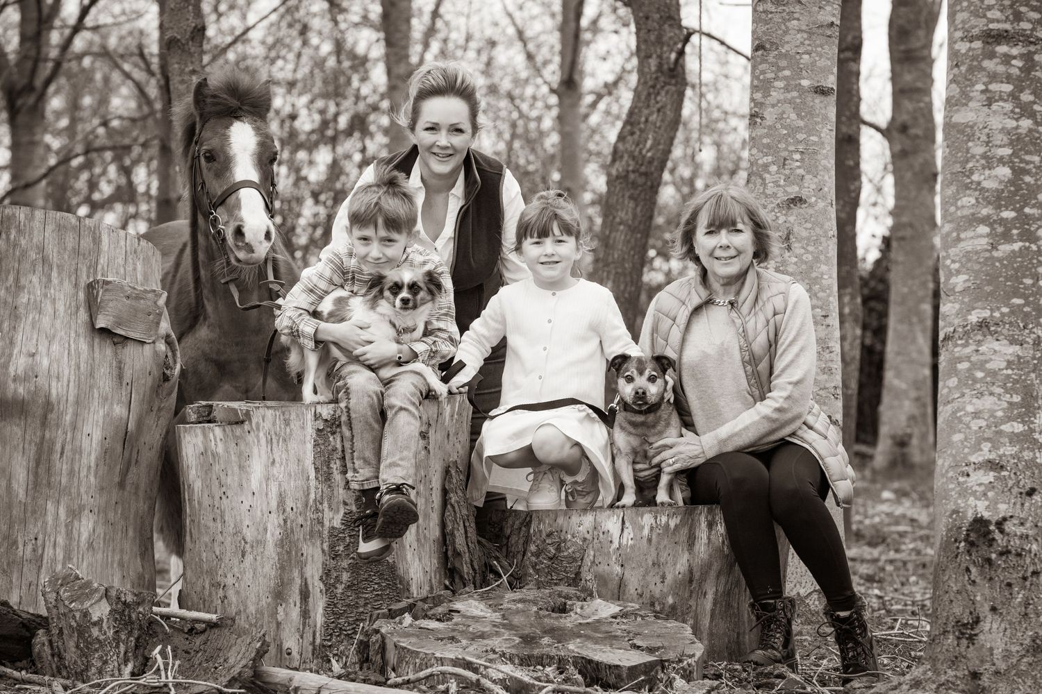 Three black and white photos show children joyfully playing and exploring among trees in a natural outdoor setting.