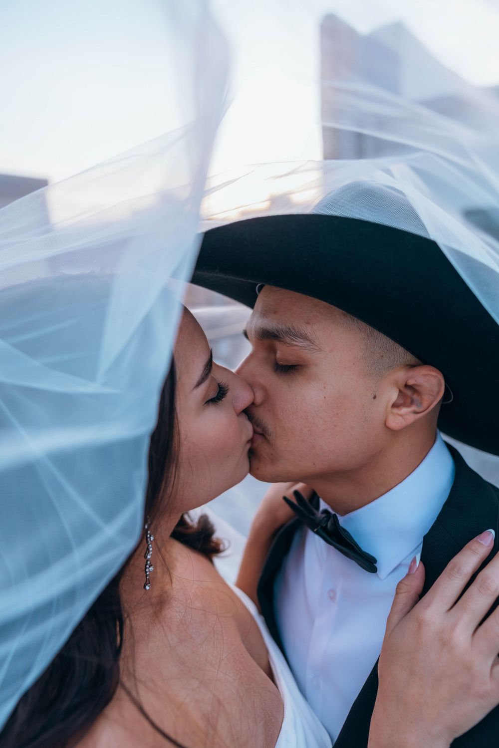 An intimate wedding portrait with flowing veil against a soft blue sky. North Carolina.