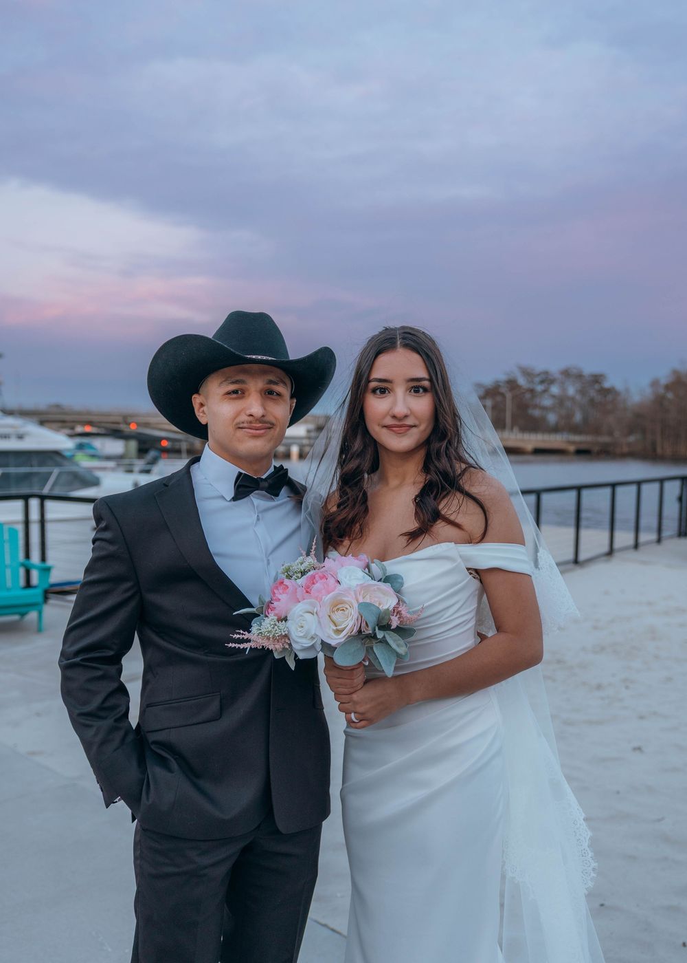 A wedding couple poses on a beach boardwalk during sunset. North Carolina.