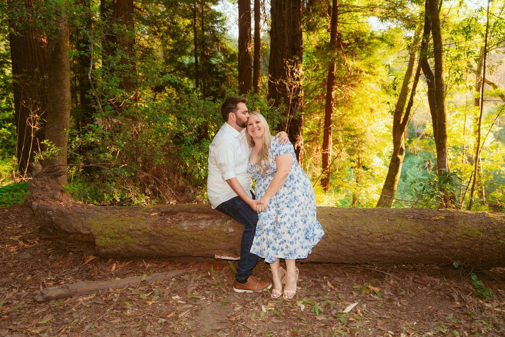 A couple shares a romantic moment on a wooded forest path during golden hour sunset lighting.