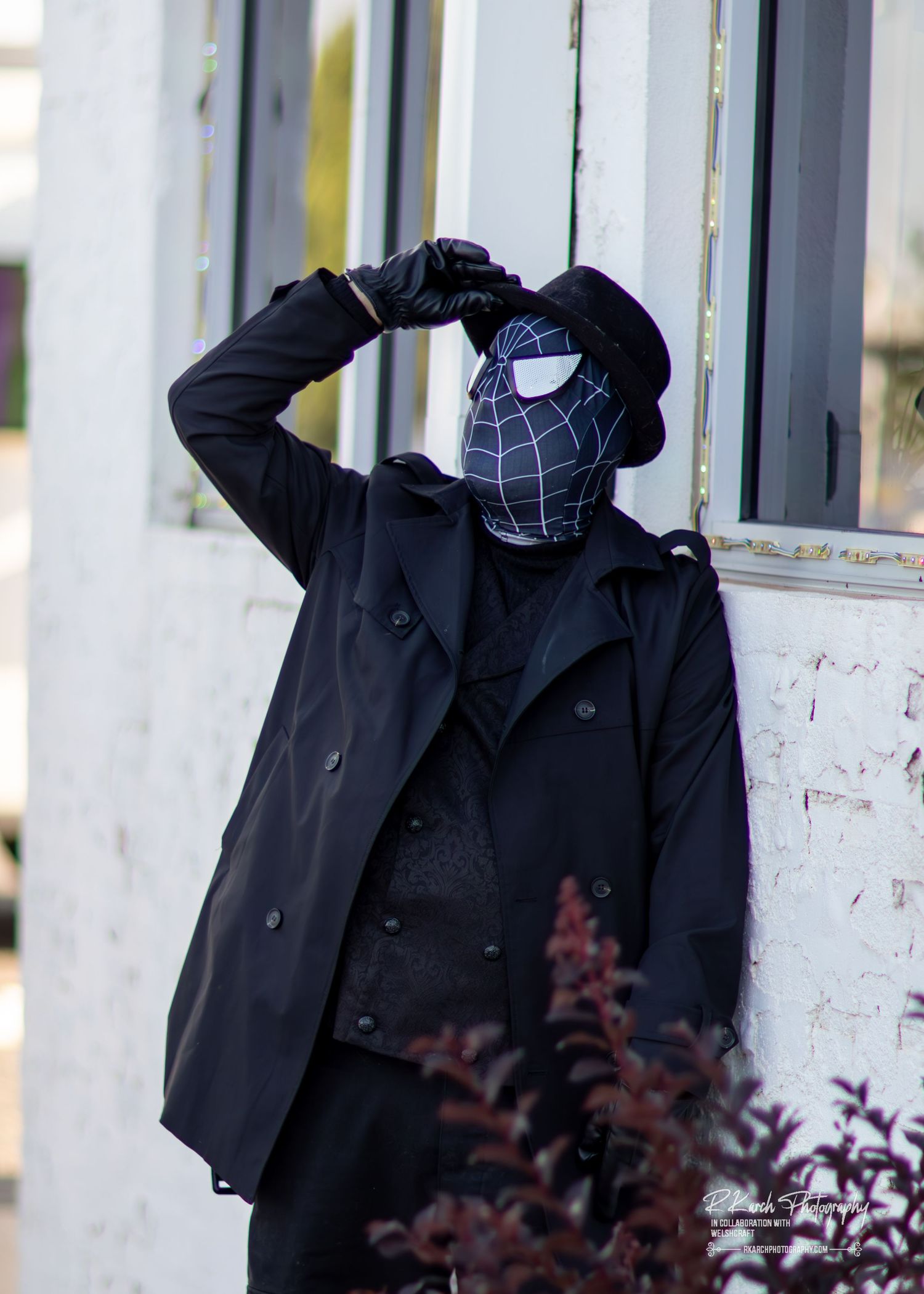 Black winter coat hanging on white railing with purple foliage in the background.