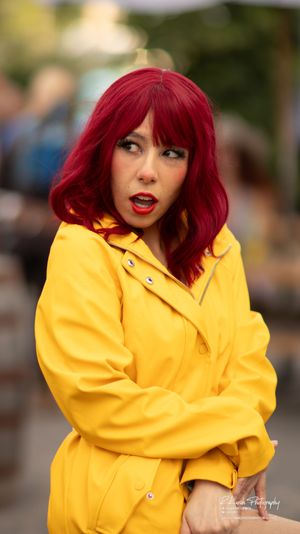 A bright yellow raincoat stands out against a blurred outdoor background with warm lighting.