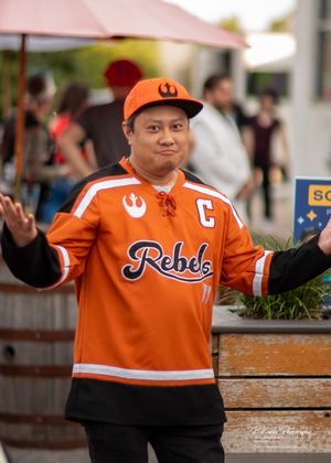Person wearing an orange sports jersey with Rebels text and Star Wars Rebel Alliance logo poses outdoors.