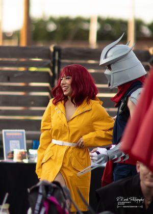 Person in yellow raincoat sharing a moment with someone in medieval-style armor at an outdoor event.