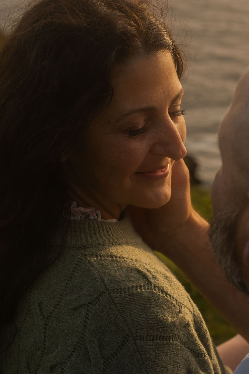Close-up portrait of someone wearing a green knit sweater bathed in warm sunset light.