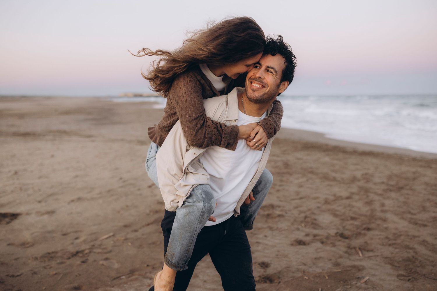 A playful moment captured between a couple on a beach at sunset.