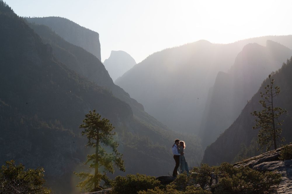 A silhouetted couple embraces against a dramatic mountain backdrop at sunset in Yosemite Valley.