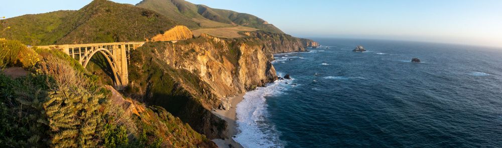 Panoramic view of Bixby Bridge along the Big Sur coastline with dramatic cliffs and ocean waves.