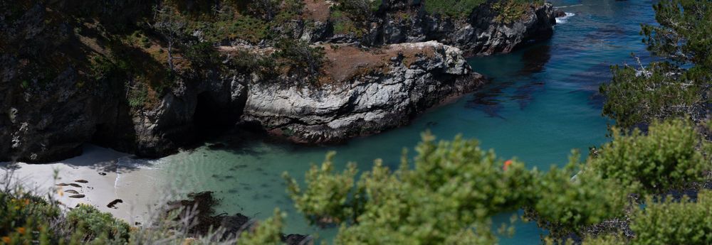 Secluded turquoise cove nestled between rocky cliffs with a small beach.