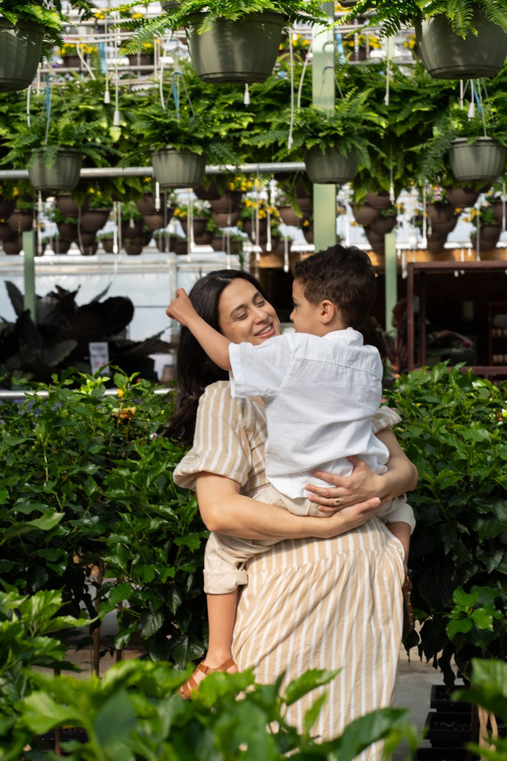 Pregnant women hugging a toddler in a greenhouse