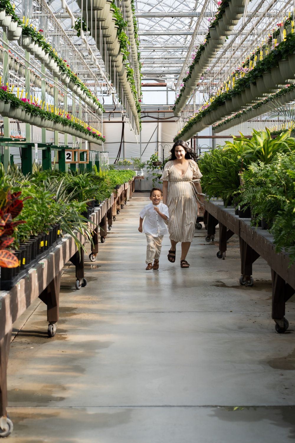 Pregnant women running with a toddler in a greenhouse