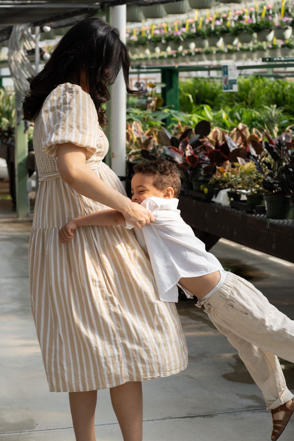Pregnant women playing with a toddler in a greenhouse