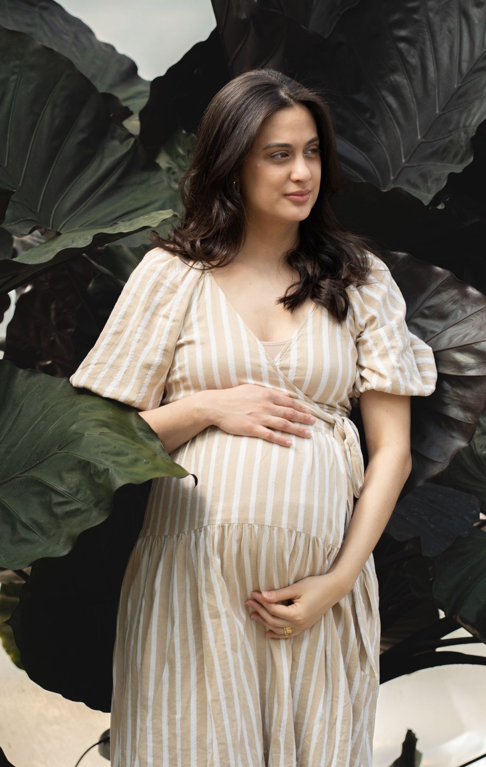 Pregnant women posing holding is belly in a greenhouse