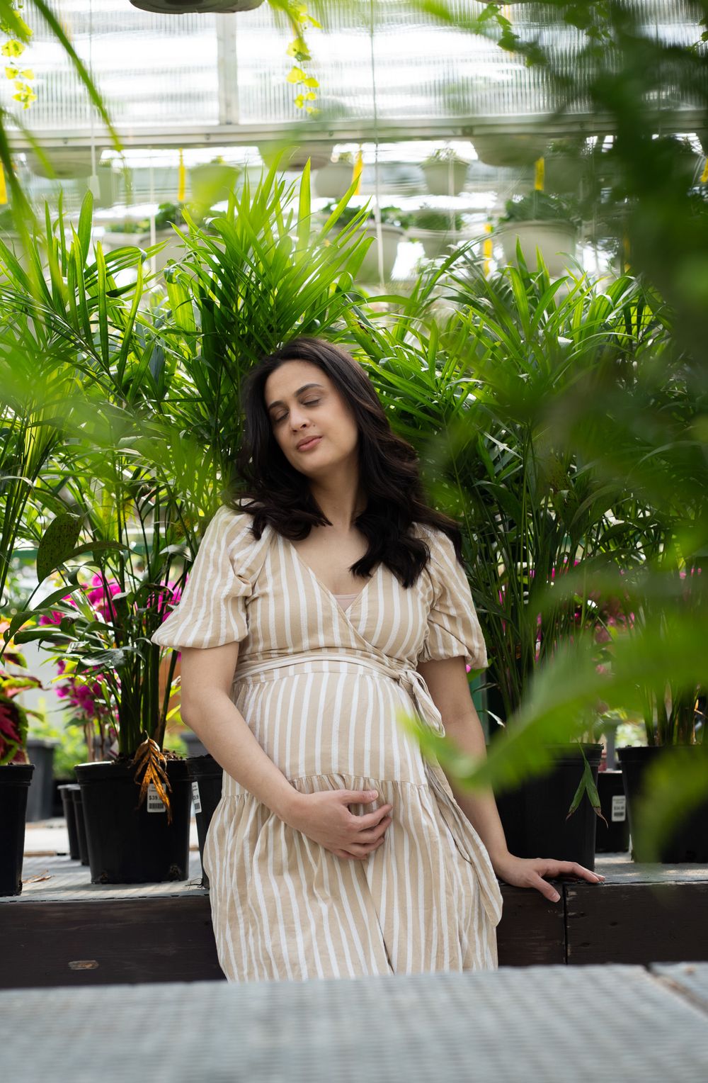 Pregnant women holding is belly in a greenhouse