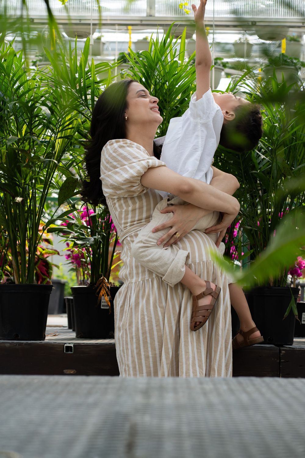 Pregnant women holding a toddler in a greenhouse