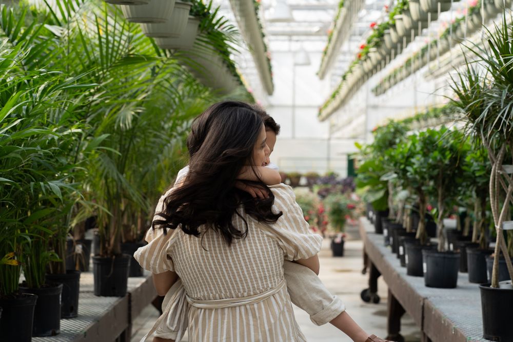 Pregnant women holding a toddler in a greenhouse
