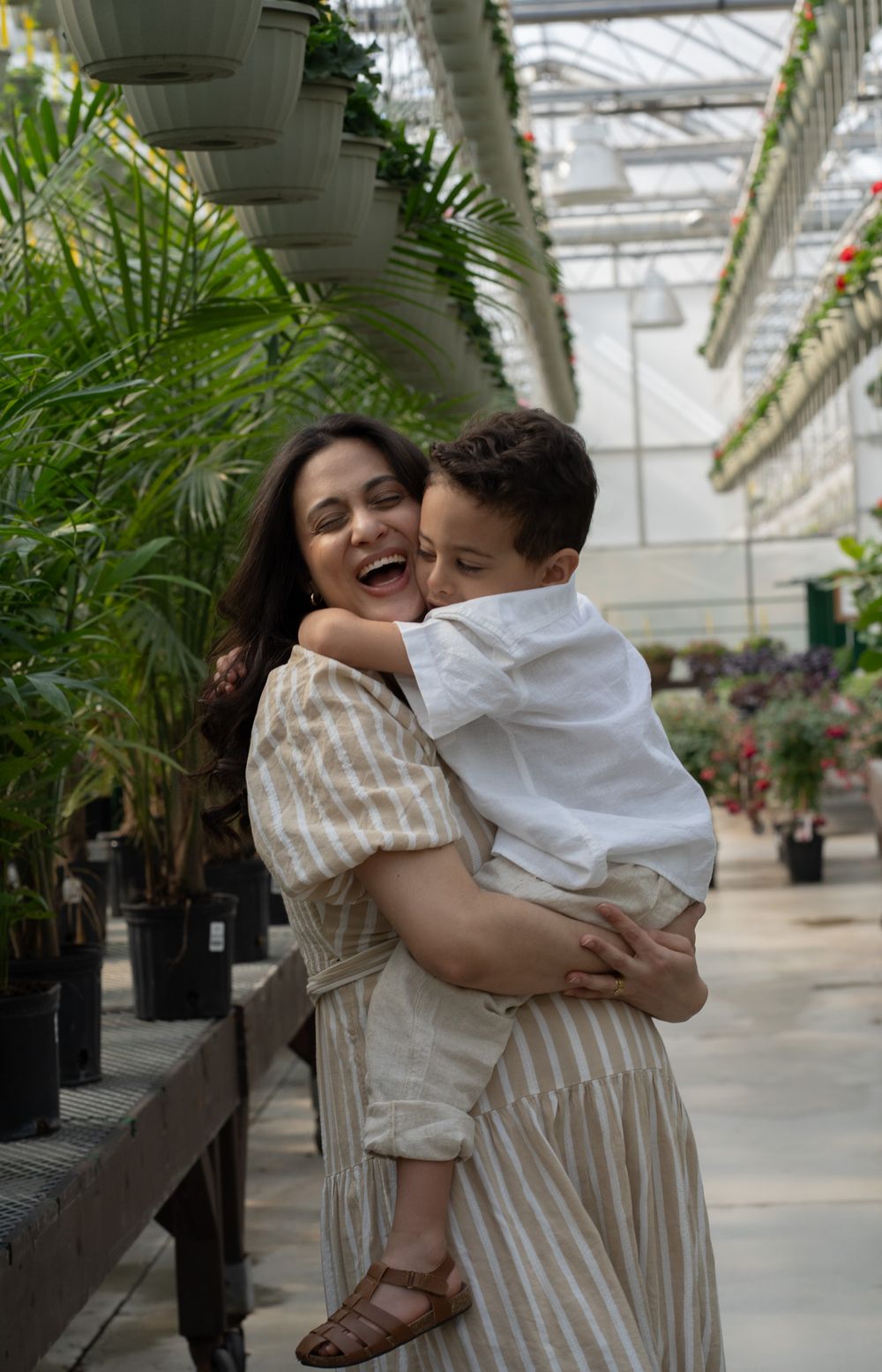 Pregnant women holding a toddler in a greenhouse