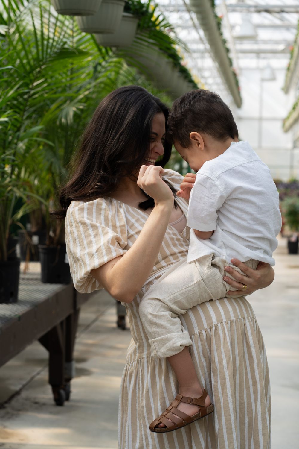 Pregnant women holding a toddler in a greenhouse