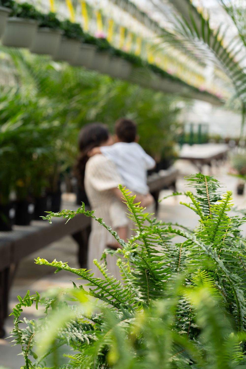Pregnant women holding a toddler in a greenhouse