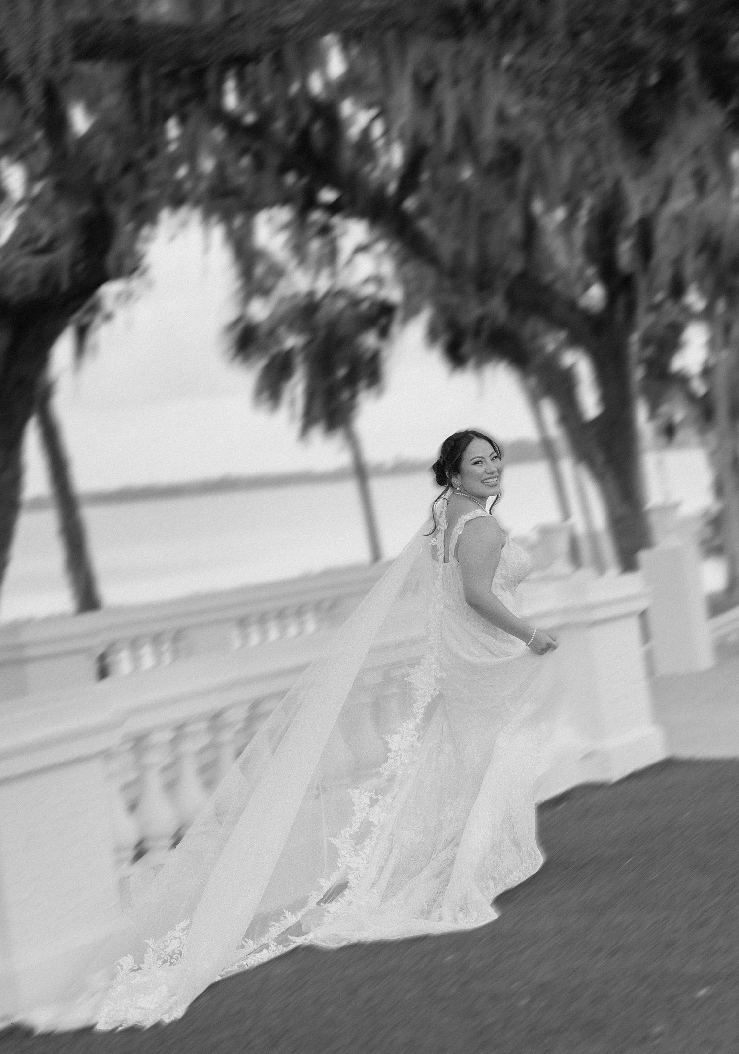 A bride in a flowing white wedding dress twirls gracefully in a black and white outdoor portrait series.
